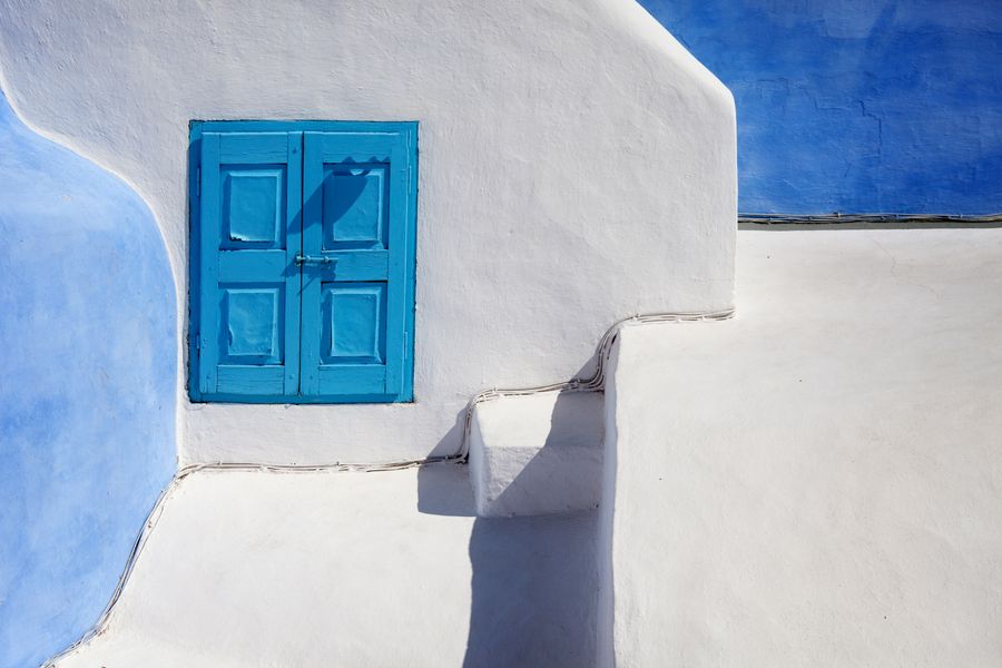 a blue wooden door on a white concrete wall