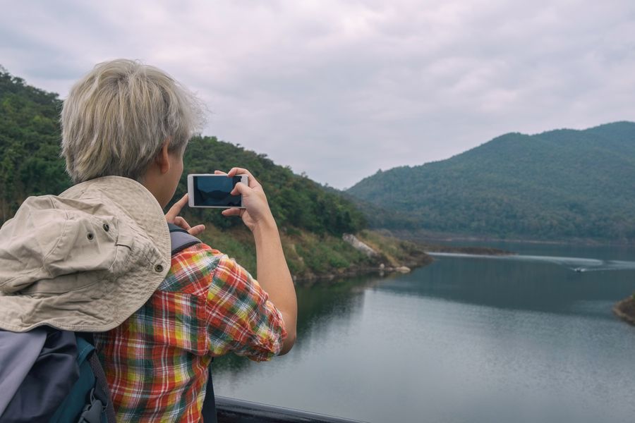 Person photographing a beautiful mountain lake view with a smartphone, enjoying outdoor adventure. — Die vernetzte Reise: Karten, Nachrichten und Übersetzung, alles auf einer eSIM.