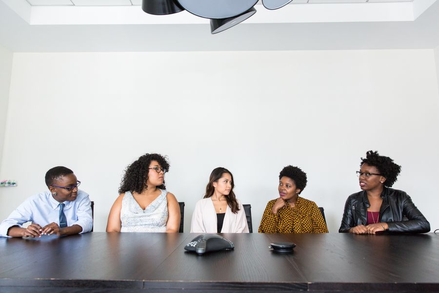 five people having conversation — Coworking abroad: laptop tethered, calls crisp, deadlines met.