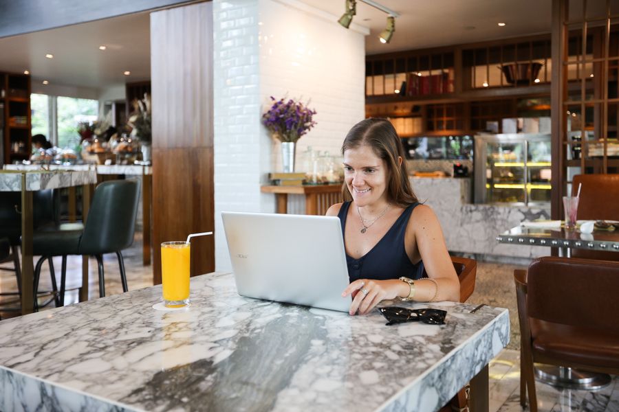 a woman inside a restaurant using a laptop — Grenzübertritte ohne Papierkram: Ausweisfotos auf dem Handy gespeichert.