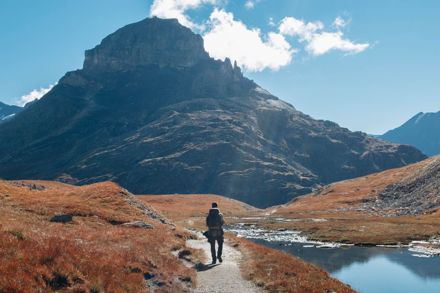 man walking at a river in mountains — Built mobile-first, because travel questions happen on phones.