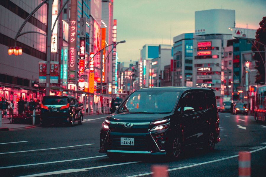 black toyota noah driving down the street in tokyo — Golden hour, fully online — photo backups upload before dinner.