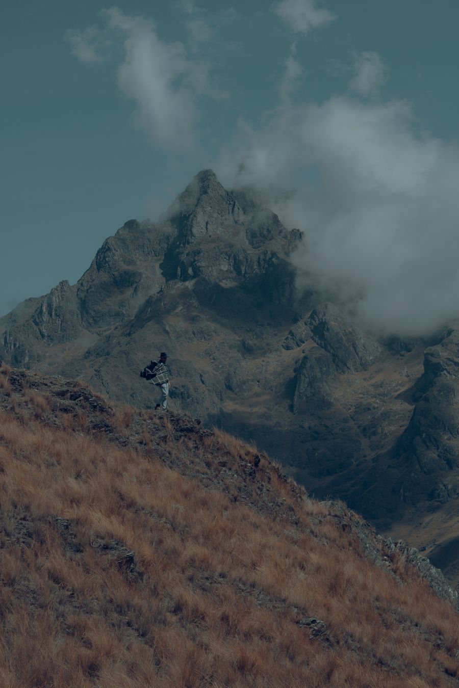 man with a backpack standing on a mountain slope