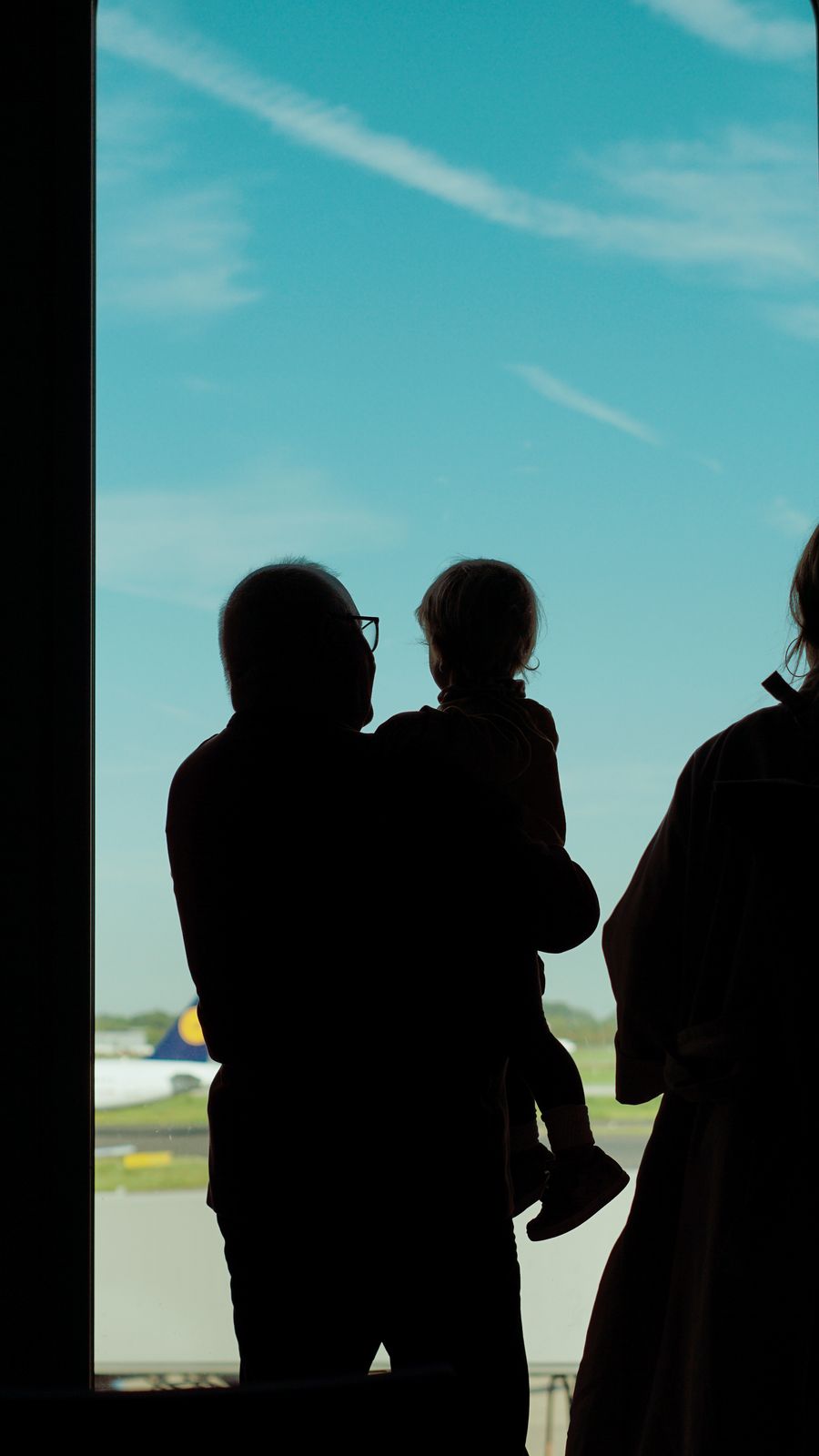 a family is silhouetted against an airport window — Data-Saver Setup: tell it about the trip, get the answer in under a minute.