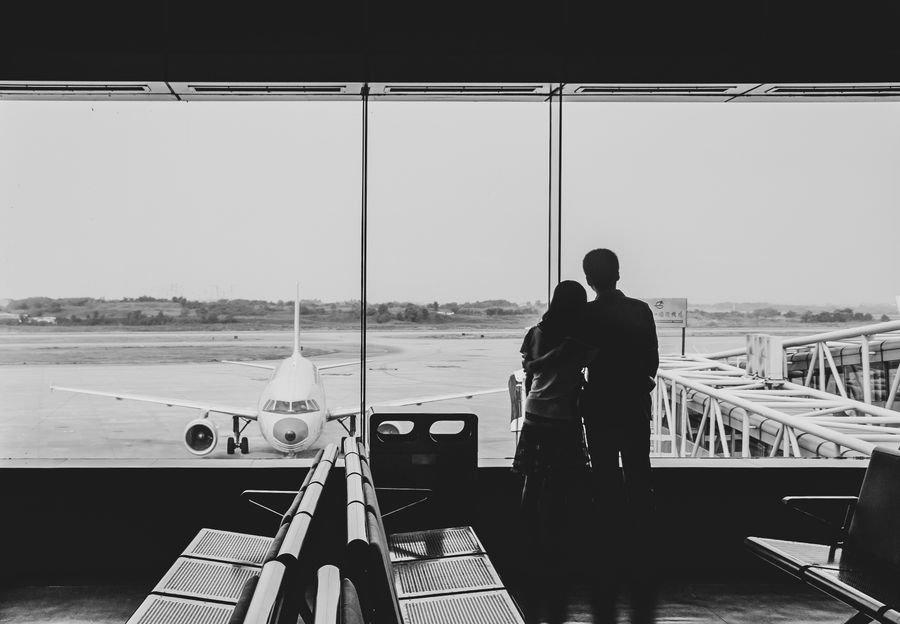 back view of couple embracing at airport — Docs: Museumsnachmittage mit streamenden Audioguides, nicht puffernd.