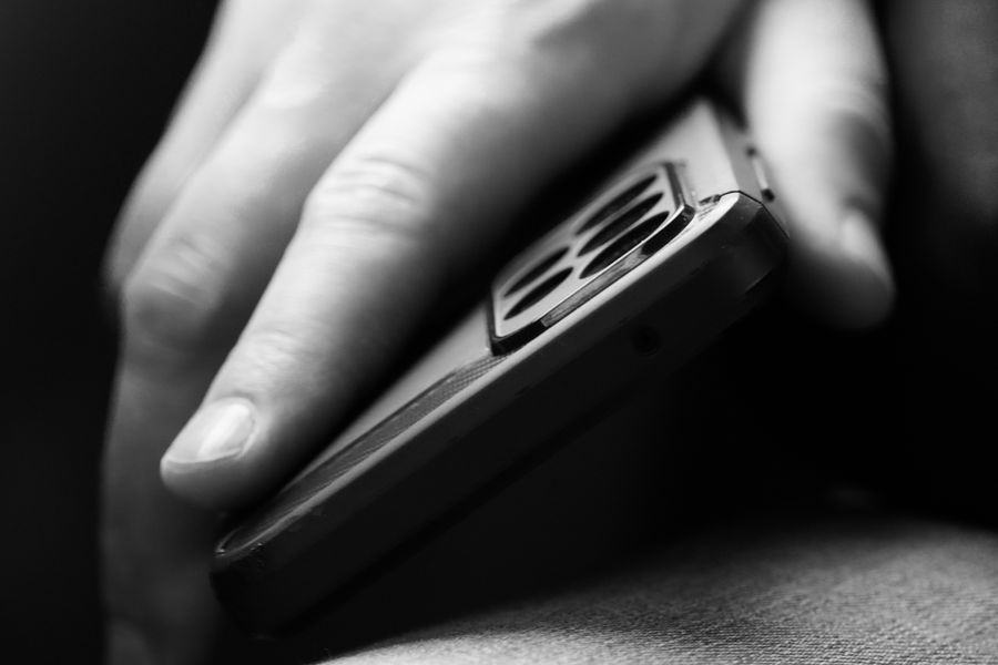 man holding mobile phone in black and white
