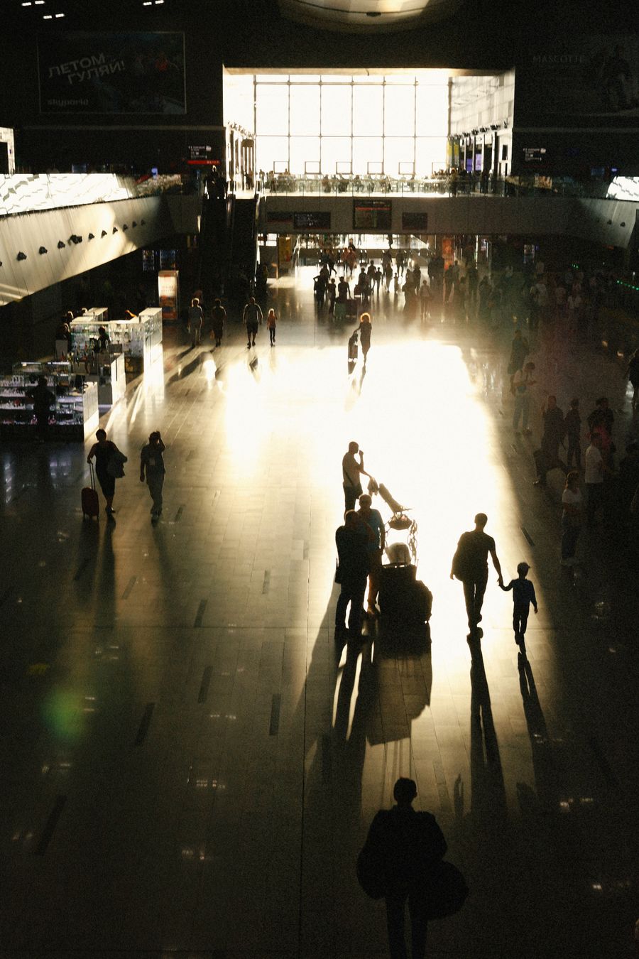busy airport terminal with silhouetted travelers — Check-in lines move faster when your documents are on your phone.