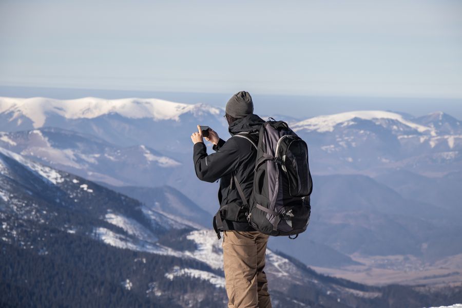 A person capturing the stunning view of snowy mountains with a smartphone. — Connection Quality Grader runs in your browser session — nothing sensitive stored against you.