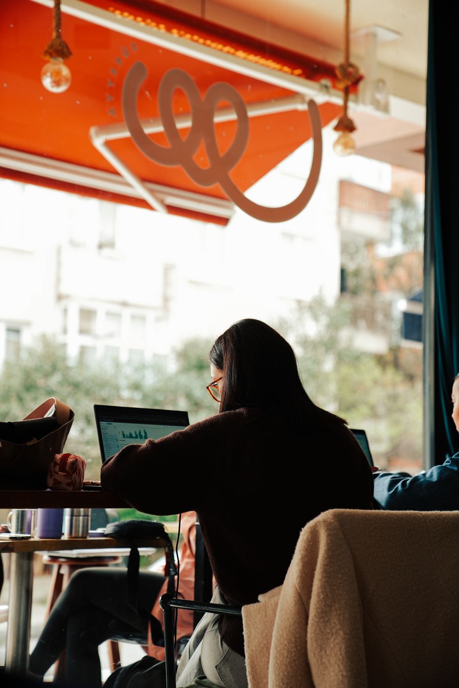 people working on laptops in a cozy cafe — From question to next step: My Active eSIMs shortens the path to a decision.