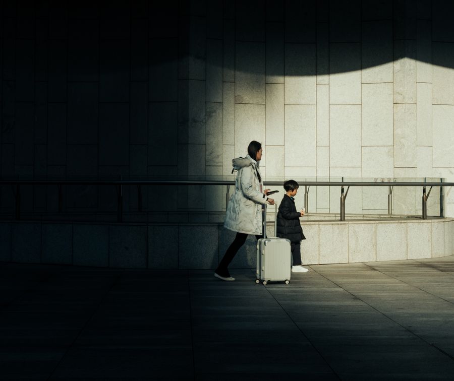 mother and child with suitcase walking indoors — Trailheads and lookouts: offline maps downloaded, just in case.