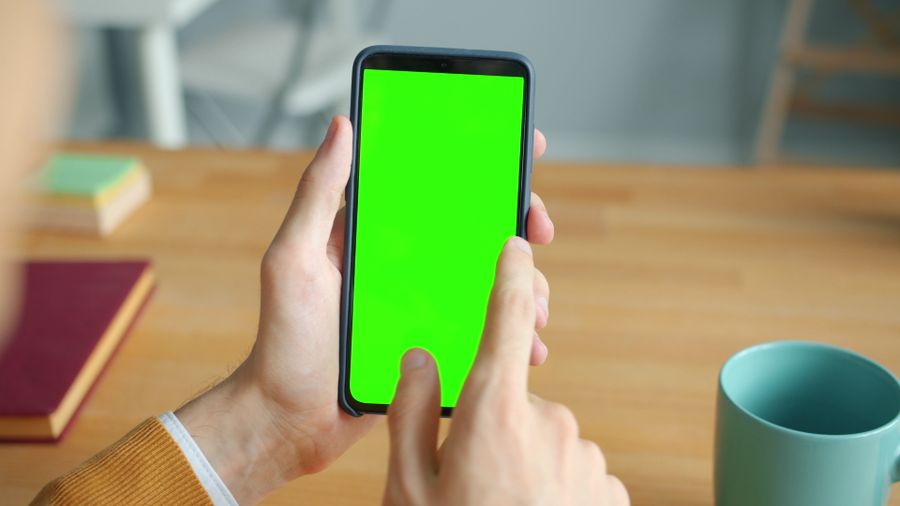 person using smartphone with green screen at desk — Von Bahnhof zu Bahnhof in Austria: Alles läuft übers Handy.