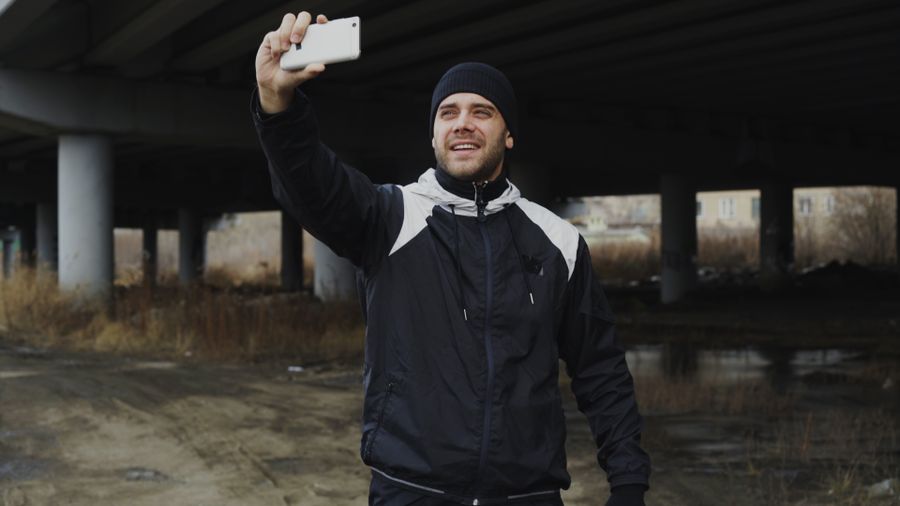 Man in sportswear taking a selfie under a bridge, capturing an urban moment. — The modern arrival: online before the seatbelt sign goes off.