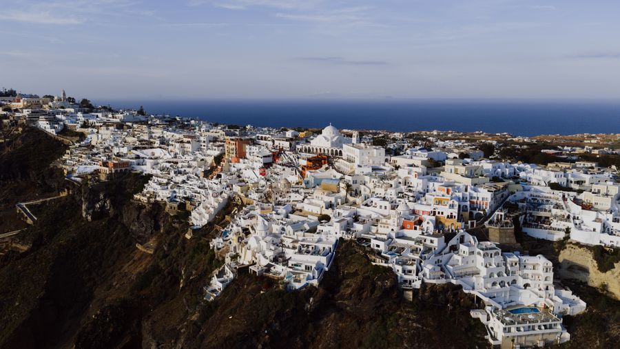 aerial view of fira santorini s white structures — Currency exchange, skipped: the phone pays at the real rate.