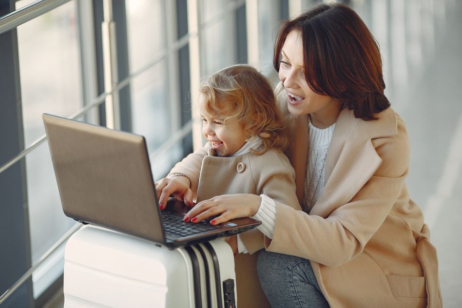 delighted mother with daughter typing on laptop in airport — Strände von COUNTRY: Parken per Handy bezahlt, Mittagessen vom Handtuch bestellt.