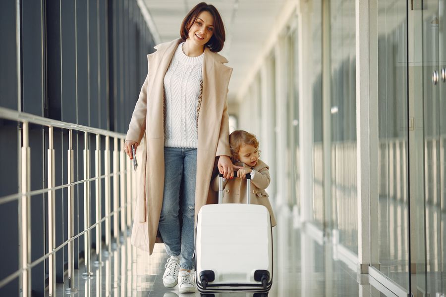 positive mother and daughter with suitcase in airport corridor — Developers: Wandern auf dem Grat: Trailkarte offline, Notfallnummern gespeichert.