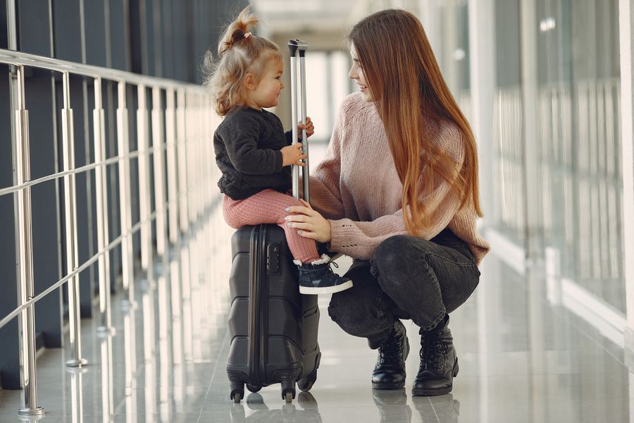 smiling mother with daughter and suitcase in airport — Harbor views with full bars: coverage where travelers actually go.