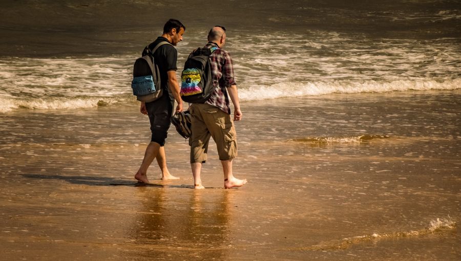 men with backpacks walking on the beach — Developers: Nachtmärkte und späte Züge — durchgehend verbunden.