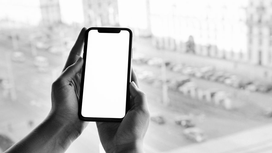 grayscale photo of person holding smartphone — Die eSIM ist ein reprogrammierbarer Chip, schon in Ihrem Handy — kein Plastik.