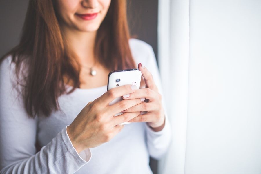 close up portrait of a young woman typing a text message on mobile phone — Support: Der Aussichtspunkt zur goldenen Stunde: Sonnenuntergang live an alle zuhause streamen.