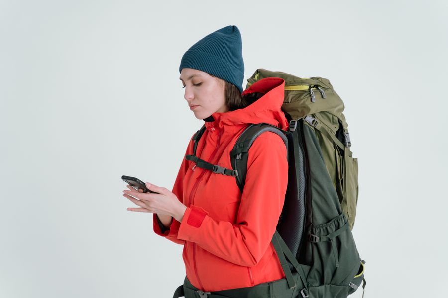 A woman in outdoor gear checking her smartphone, ready for adventure. — From question to next step: Free Wi-Fi Finder shortens the path to a decision.