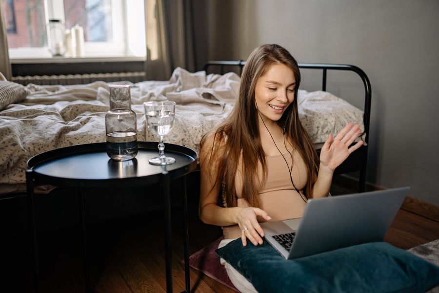 a woman waving her hand while looking at the screen of the laptop — Skilifte in Austria: Skipass auf dem Handy, Bedingungen beim Frühstück geprüft.