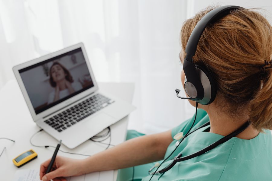 woman wearing headphones while video calling to patient