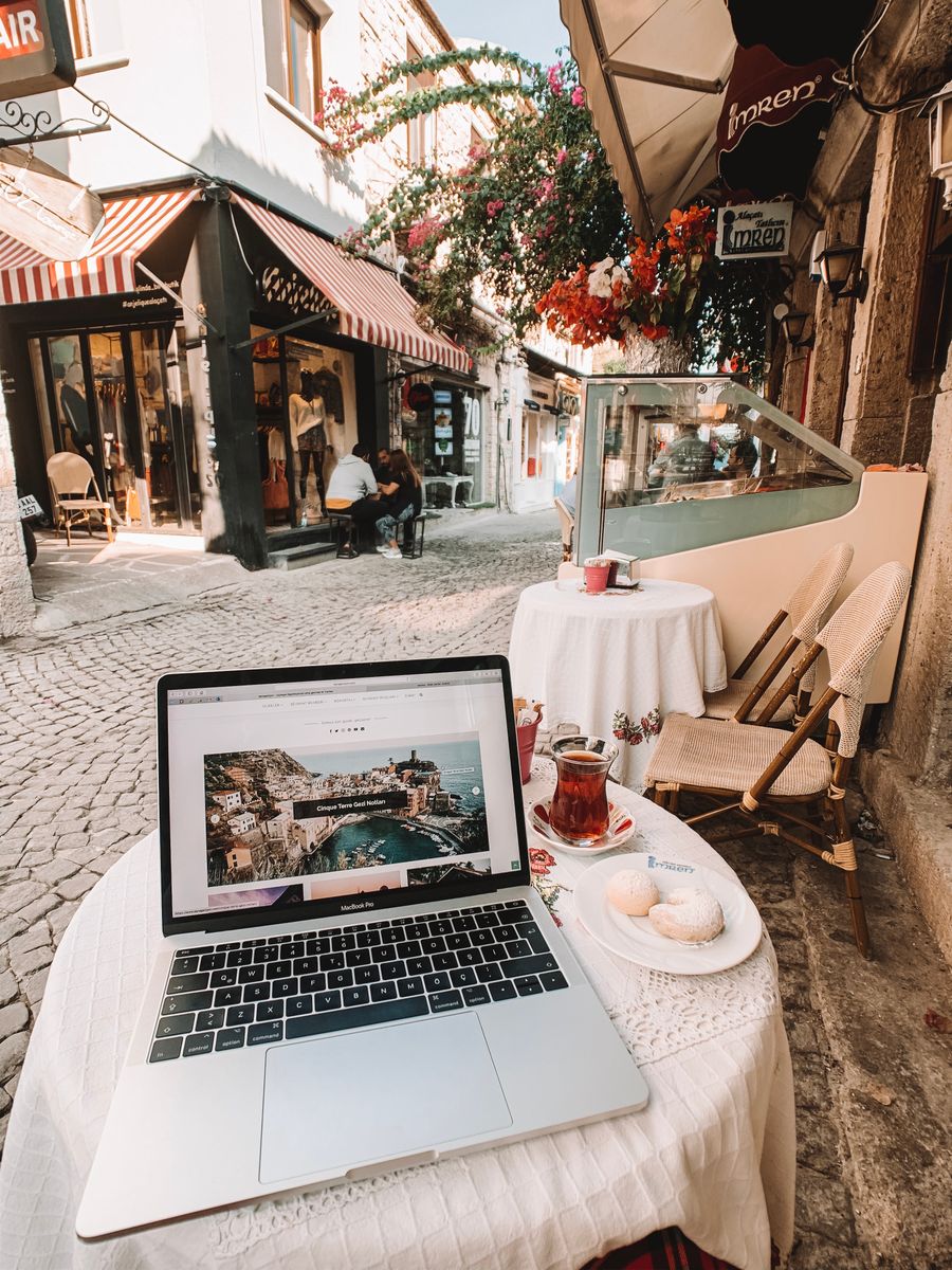 laptop standing on a table outside of a cafe with view of an alley — No account, no install, no waiting — Resend eSIM QR Code loads and answers.