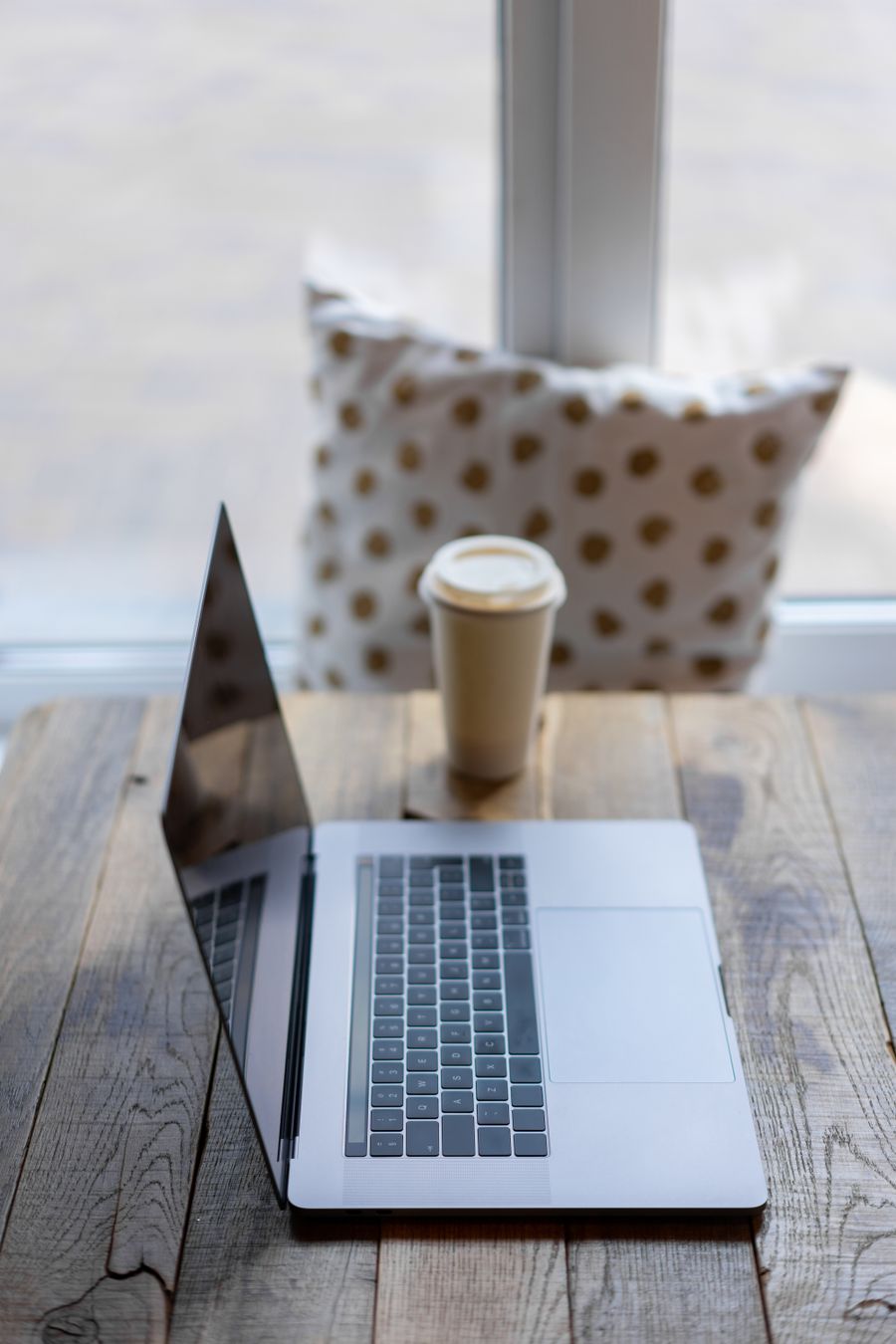 silver macbook on wooden table beside a paper cup — Family group chat: location shared, dinner plans settled in minutes.