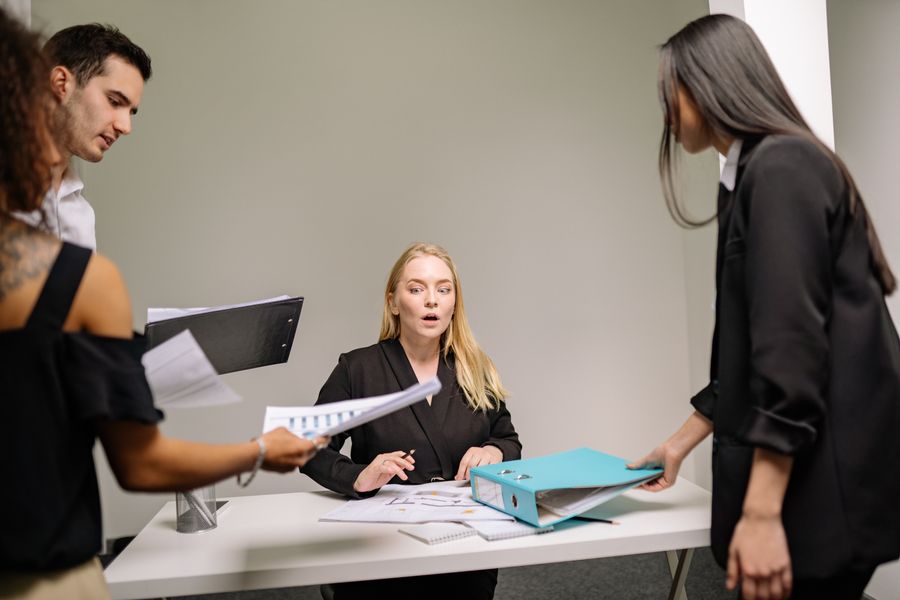 a woman in black blazer sitting at the desk with documents — Latency to Destination works for anonymous visitors — answers first, signup never forced.