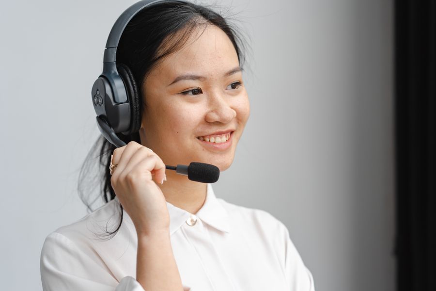 close up photo of a woman holding the microphone of her black headset — Die Austria-SIM-Schlange, komplett übersprungen: installiert, bevor die Flugzeugtür aufging.