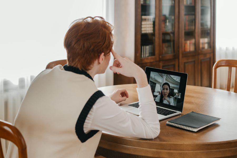 a man having a video call on his laptop — Support: Wechselstube, übersprungen: Das Handy zahlt zum echten Kurs.