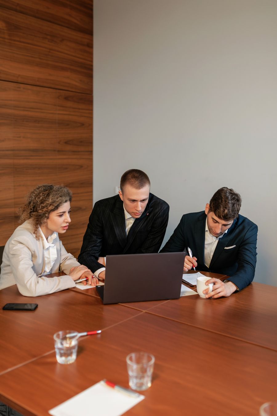 colleagues looking at a computer during a meeting — Der Agent verkauft nie hoch; er passt den Tarif an die Reise an.