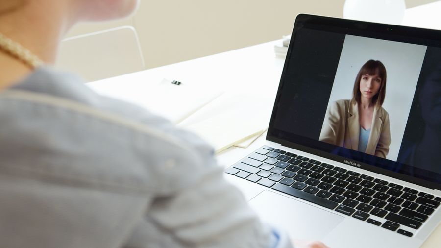 photo of a woman on the screen of a laptop — The business trip: client deck synced, video call joined from the taxi.