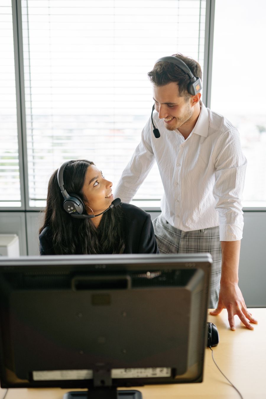 man and woman wearing black headset smiling at each other — Inselzeit, Onlinezeit: Fähren, Strände und voller Empfang.