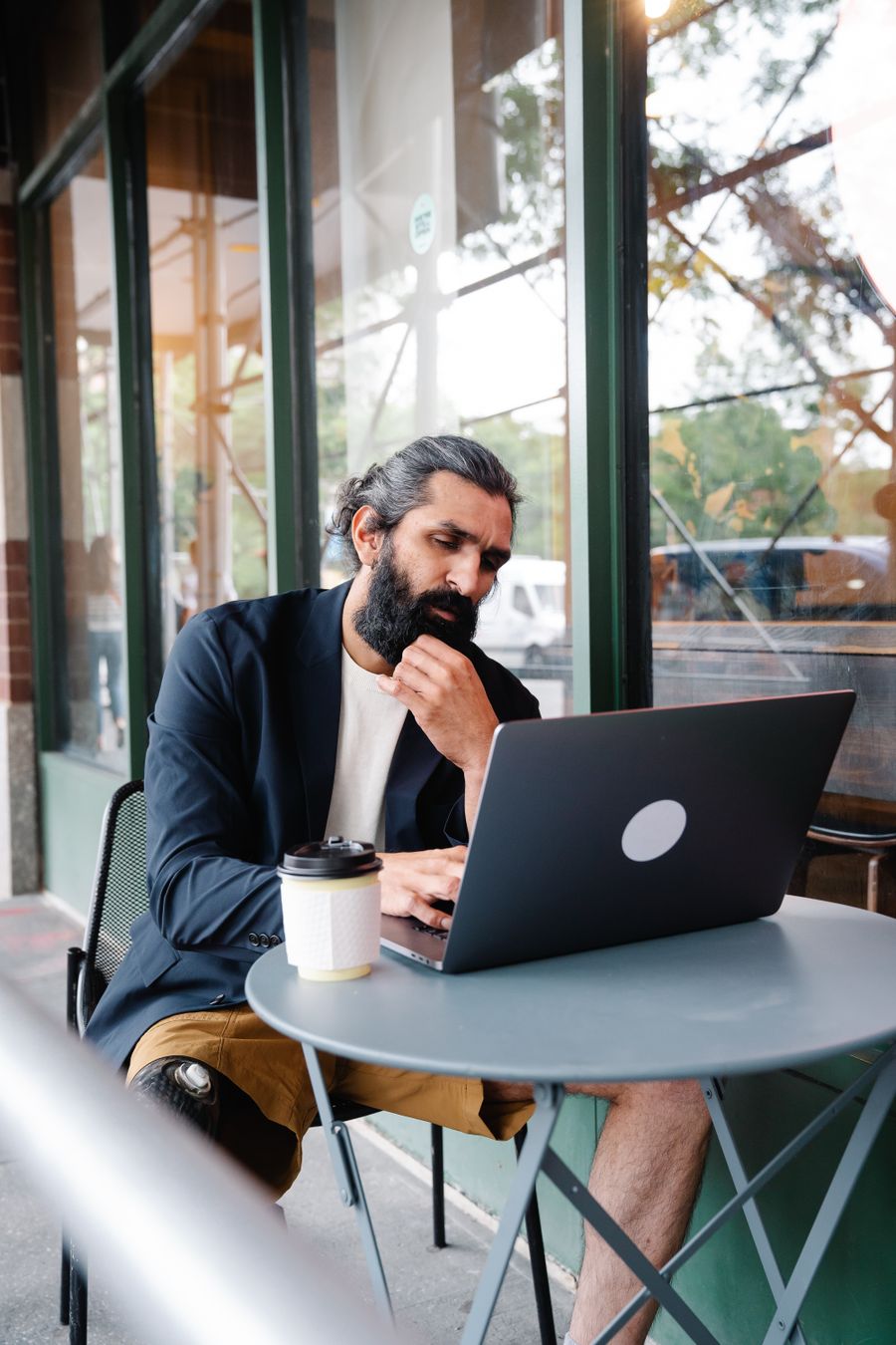 pensive man looking at laptop — Coworking im Ausland: Laptop getethert, Anrufe klar, Deadlines gehalten.