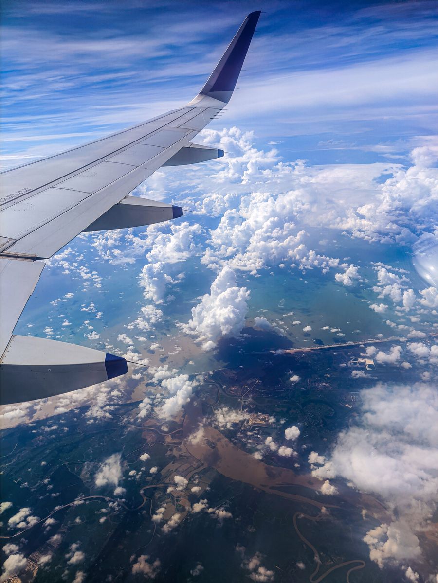 photo of an airplane wing over white clouds — Travelers stay online from the moment they land — no SIM queues, no roaming shock.